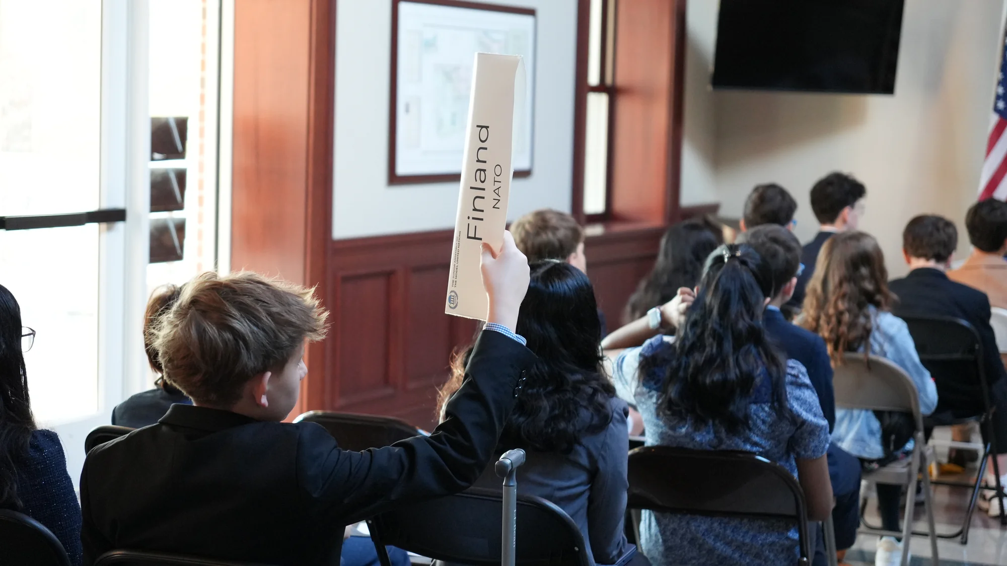 Delegado de Modelo ONU levantando cartel durante sesión de comité